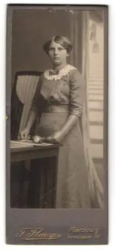 Fotografie F. Flarup, Flensburg, Grossestr. 75, Junge Dame im kleid mit Taillengürtel an einem Tisch