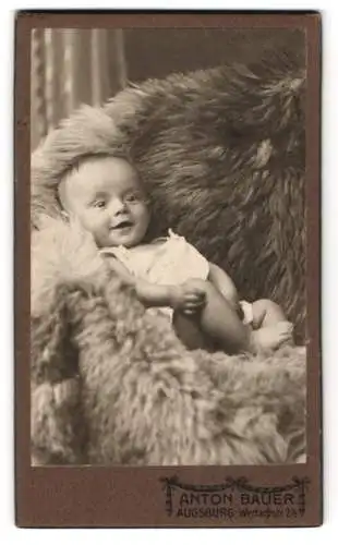 Fotografie Anton Bauer, Augsburg, Wertachstr. 2, Kleines Kind auf einem Pelz mit einem neugierigen Grinsen im Gesicht