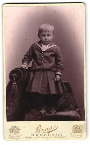 Fotografie Grass, Mannheim, Kleines Kind im Kleid mit Matrosenelementen, mit schüchternem Blick