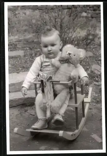 Fotografie Baby mit Teddybär / Teddy im Schaukelstuhl sitzend
