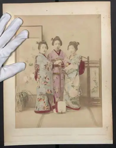 Fotografie unbekannter Fotograf und Ort, drei Geishas im Kimono, Shamisen, Handkoloriert, Rückseite junge Geisha Tracht