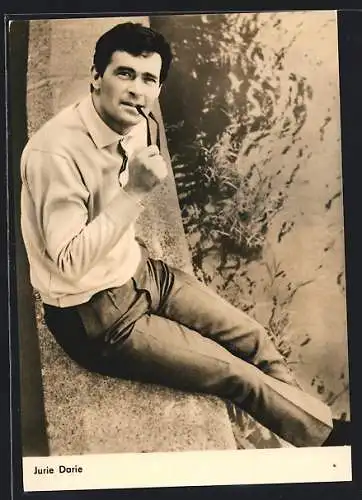 AK Schauspieler Jurie Darie auf Ufermauer sitzend mit Brille im Mund