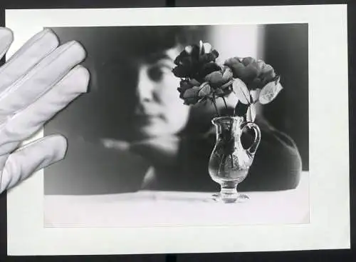 Fotografie unbekannter Fotograf und Ort, stilistisch eingefangene Vase mit Rosen vor einer Person