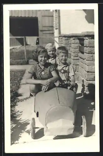 AK Kinder in einem Spielzeug-Auto im Garten