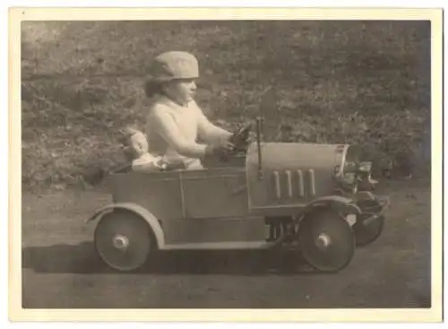 Fotografie Tretauto Cebaso, niedliches Kind mit Spielzeug-Blechauto und Puppe