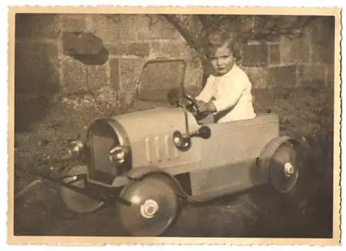 Fotografie Tretauto Cebaso, niedliches Kind sitzt im Spielzeug-Blechauto