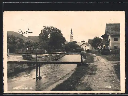 AK Munderfing /O. Ö., Strassenpartie am Fluss, im Hintergrund die Kirche