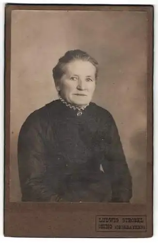 Fotografie Luwig Strobel, Obing /Oberbayern, Ältere Dame im schwarzen Kleid mit einer Portrait-Brosche am Kragen