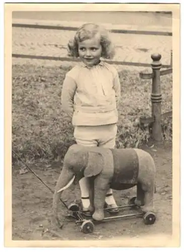 Fotografie Spielzeug, niedliches Mädchen nebst Stoff-Elefant auf Rädern