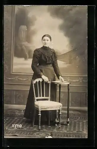 Foto-AK Frau im Kleid am Tisch in einer Studiokulisse