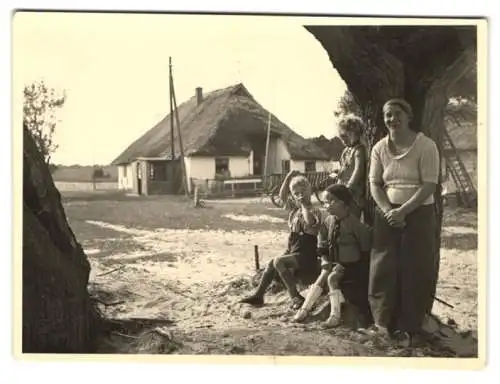 Fotografie unbekannter Fotograf, Ansicht Kolberger Deep, Mutter mit ihren Kindern vom Reetdach Haus im Ort, 1940