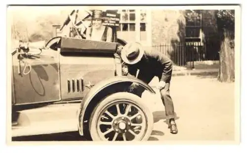 Fotografie Auto Mann kurbelt seine Auto an mit Handkurbel, Holzspeichen