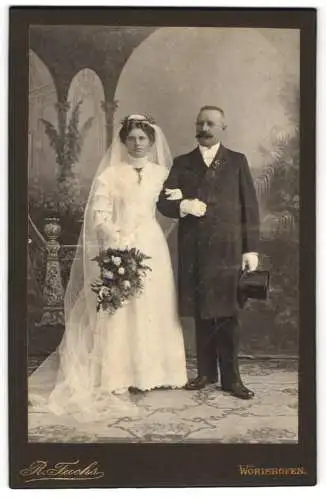 Fotografie R. Fuchs, Wörishofen, Ehepaar am Hochzeitstag im Brautkleid und Anzug mit Zylinder
