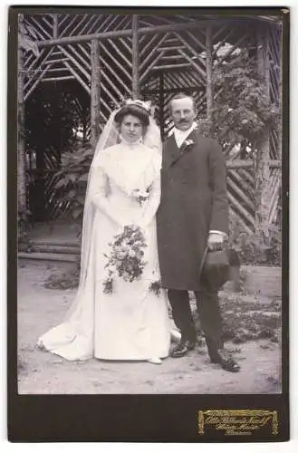 Fotografie Otto Böhms Nachf., Passau, Brautpaar im Hochzeitskleid nebst Mann im Anzug mit Zylinder