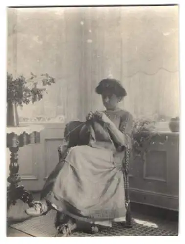 Fotografie unbekannter Fotograf und Ort, junge Frau posiert Strickend im Sessel sitzend, Hausarbeit