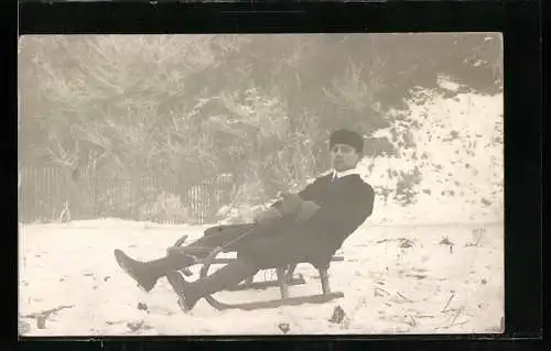 Foto-AK Junger Mann auf einem Schlitten im Schnee