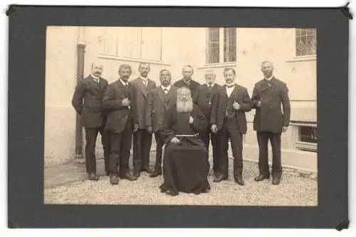 Fotografie unbekannter Fotograf und Ort, betagter Geistlicher Führer von Herren im Anzug umringt
