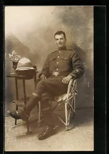 AK Junger britischer Soldat in Uniform mit Sporen sitzt an einem kleinen Tisch