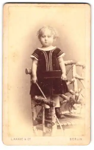 Fotografie L. Haase & Co., Berlin, Unter den Linden 62, Süsses Kind im Kleidchen auf einem Holzstuhl