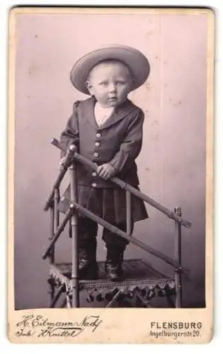Fotografie H. Eilmann Nachf. Knittel, Flensburg, Angelburgerstr. 20, Lustiges Kleinkind mit feiner Kleidung und Hut