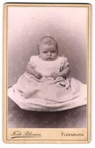 Fotografie Fritz Petersen, Flensburg, Friesische Strasse 2, Baby mit unzufriedener Miene im weissen Kleid