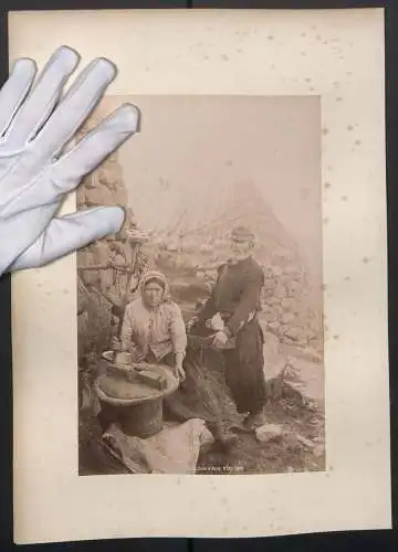 Fotografie unbekannter Fotograf, Ansicht Skye, schottische Bauern in zerschlissener Kleidung beim Mehl mahlen, Tracht