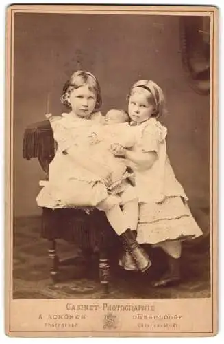 Fotografie A. Schönen, Düsseldorf, Casernenstr. 61, Mädchen halten gemeinsam Baby im Taufkleid