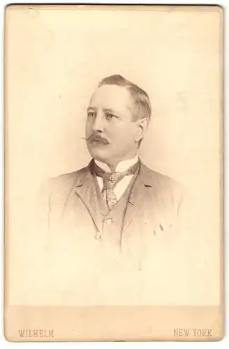 Fotografie Wilhelm, New York, Bürgerlicher mit Zwirbelschnurrbart und Seitenscheitel im hellen Dreiteiler