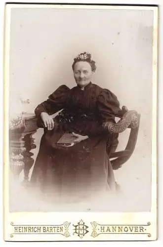 Fotografie Heinrich Barten, Hannover, Georg-Strasse 1, Lächelnde ältere Dame mit Haarschmuck im schwarzen Puffärmelkleid