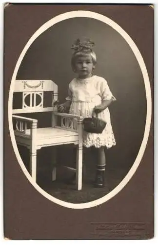 Fotografie Adolf Bruns, Hamburg, Hoheluftchaussee 131 /133, Die kleine Wilma Schwen mit Korb und einer Schleife im Haar