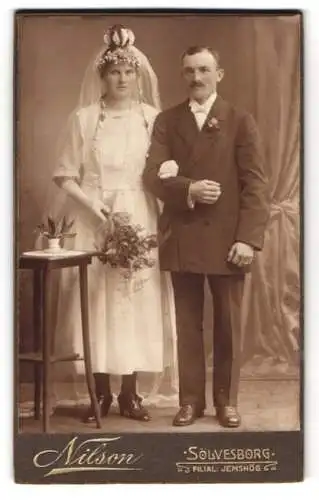 Fotografie Nilson, Sölvesborg, schwedisches Brautpaar im Hochzeitskleid und im Anzug mit Brautstrauss