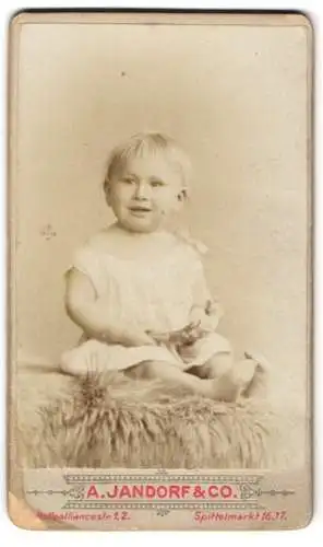 Fotografie A. Jandorf & Co., Berlin, Spittelmarkt 16, Artur Hilger als Baby im weissen Kleid am Lächeln