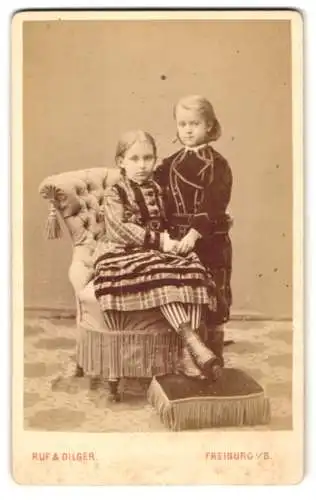 Fotografie Ruf & Dilger, Freiburg, Ludwigstr. 2, Geschwister Nelly und Otto in dunklen Kleidern auf einem Sessel