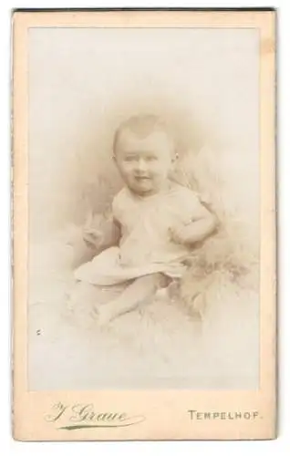 Fotografie J. Graue, Tempelhof, Ringbahnstr. 60, Süsses Baby Blümel im weissen Kleid auf einem Fell