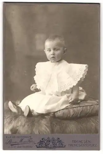Fotografie Stern M. ès. Fia, Trencsén, Baby im Spitzenkleid auf einem Kissen