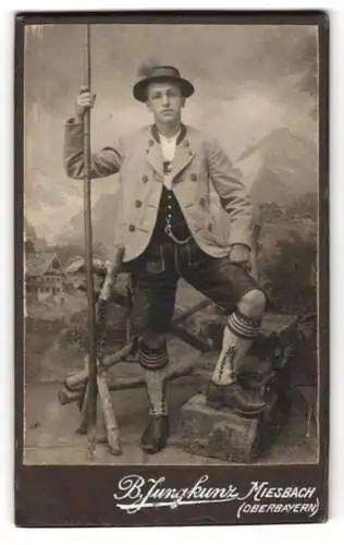 Fotografie B. Jungkunz, Miesbach, junger Mann in bayerischer Tracht, Lederhose und Wanderstock