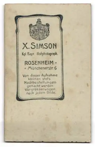 Fotografie X. Simson, Rosenheim, junge Frau in bayerischer Tracht mit Hut vor einer Studiokulisse