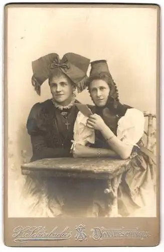 Fotografie X. Schönbucher, Donaueschingen, zwei Frauen in Trachtenkleidern mit Kopfschleife und Trachtenhut