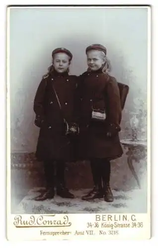 Fotografie Rud. Conrad, Berlin, zwei Mädchen in Wintermantel mit Schulranzen und Umhängetasche, Schulanfang
