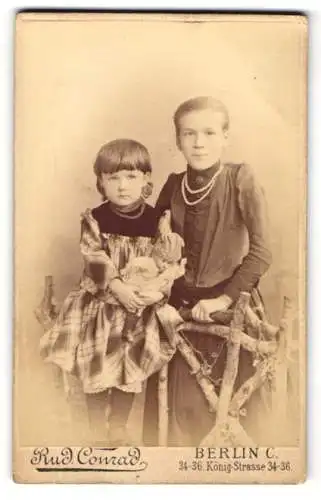 Fotografie Rud. Conrad, Berlin, Königstrasse 34-36, Mädchen mit Halskette & Puppe wohl gekleidet