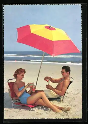 AK Ein Paar in Bademode genehmigt sich unterm Sonnenschirm ein kühles Getränk