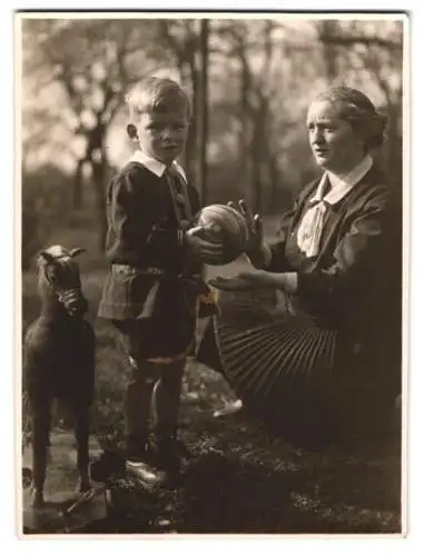 Fotografie Blonder Knabe mit Ball nebst Spielzeug-Pferd zu Ostern 1930