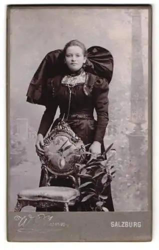 Fotografie Wilhelm Mann, Salzburg, Marktplatz, junge Frau im dunklen Trachtenkleid mit Schleife