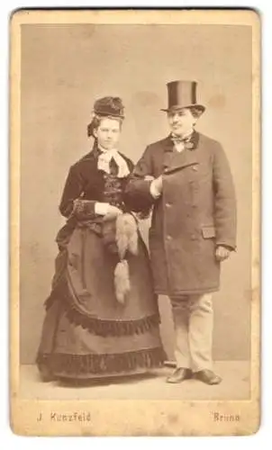 Fotografie J. Kunzfeld, Brünn, Ehepaar Gottfried Richter im dunklen Winterkleid mit Muff und im Anzug mit Zylinder