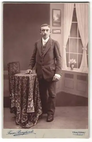 Fotografie Franz Burghardt, Trautenau, junger Mann im Anzug posiert in einer Studiokulisse