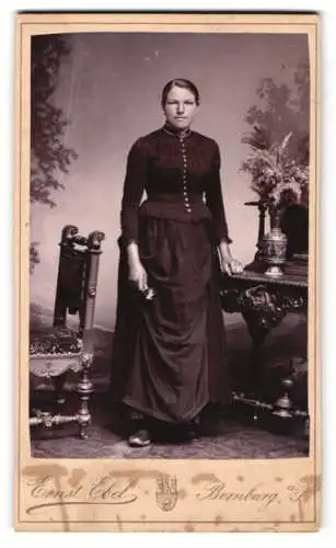 Fotografie Ernst Ebel, Bernburg a. S., Dame im dunklen Kleid stehend neben einem Sekretär