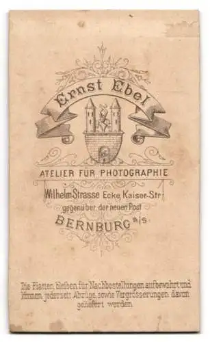 Fotografie Ernst Ebel, Bernburg a. S., Dame im dunklen Kleid stehend neben einem Sekretär