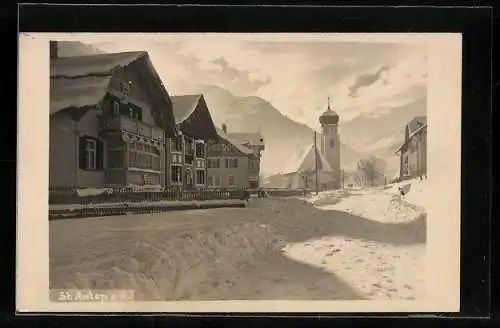 AK St. Anton a. A., Strassenpartie mit Kirche im Schnee