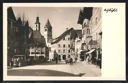 AK Kitzbühel, Strassenpartie mit Friseur Da Pont und Blick auf Kirchtürme