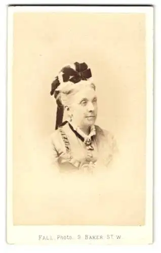 Fotografie T. Fall, London, Baker Street 9, Schöne Dame im hellen Kleid mit schwarzer Schleife im Haar und Brosche
